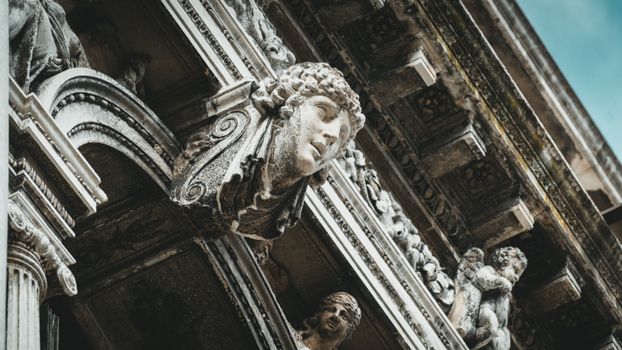 Detailed view of architectural sculptures on a Venetian building facade, showcasing historical artistry.