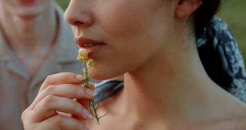 Man Looking at a Woman Putting Flowers on her Face