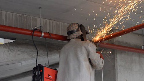 Man Working on Pipe with Angle Grinder