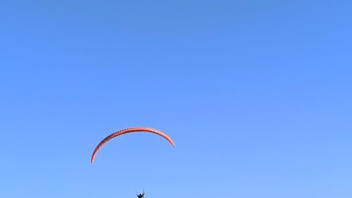 Person Paragliding Against Blue Sky