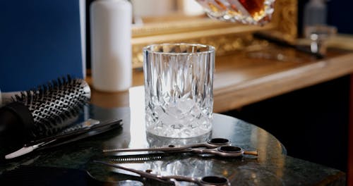 A Person Pouring Whiskey on a Drinking Glass with Ice Cubes