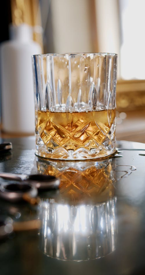 A Person Adding Whiskey on a Drinking Glass