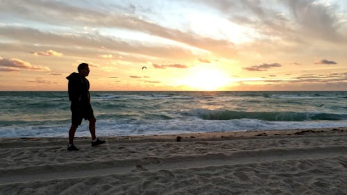 Man Walking on Beach during Sunrise