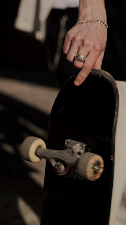 Close-Up View of Man with Tattoo on Hand Holding Skateboard