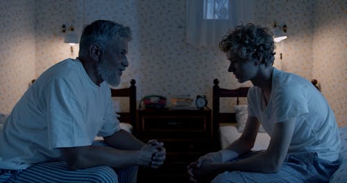 Elderly Man and a Boy Having a Conversation in Bedroom