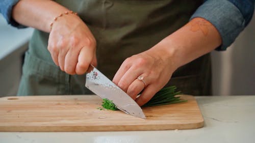 A Person Cutting Chives on a Chopping Board