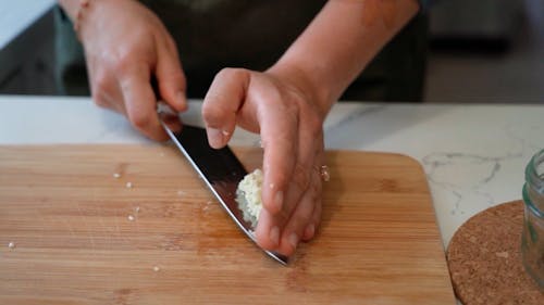 A Person Placing Chopped Garlic in a Glass Jar