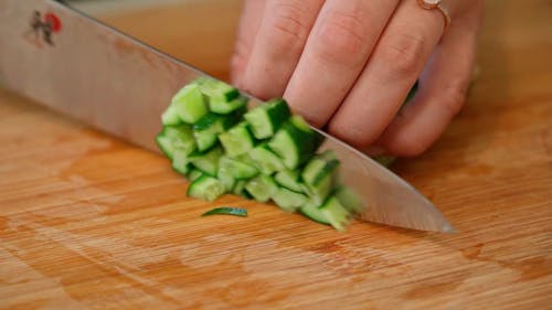 A Person Cutting Cucumber into Cubes