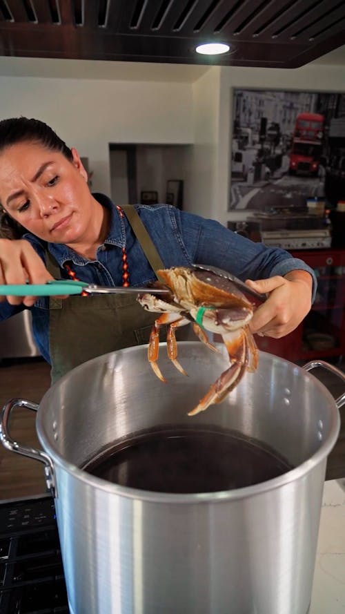 A Woman Lowering a Dungeness Crab into a Pot