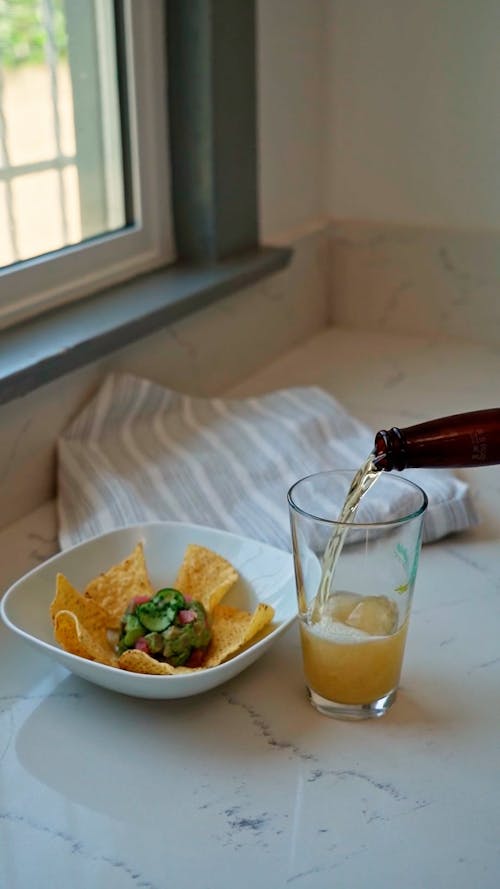 A Glass of Beer and Nachos on a Marble Surface
