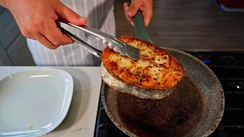 A Person Transferring the Food from Frying Pan to the Plate Using Tongs