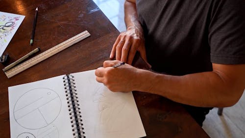 A Person Sketching in a Spiral Notebook