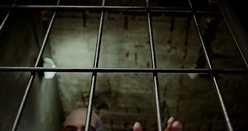 A Low Angle Shot of an Inmate Trembling Inside the Cell