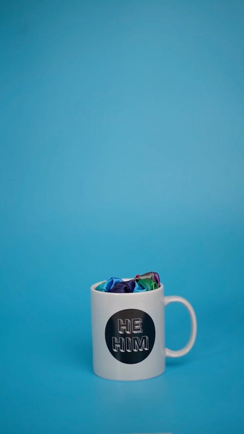 Person Putting a Pride Sign in a Mug with Inscription