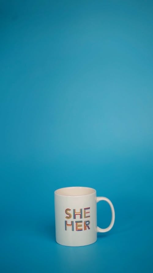 A Hand Placing a Pride Sign in a Mug with Inscription