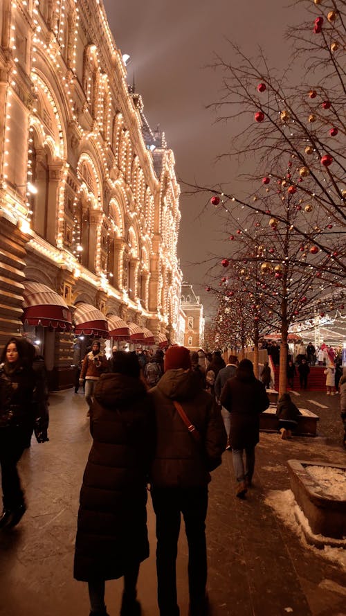 People Walking by Christmas Decorations at Night