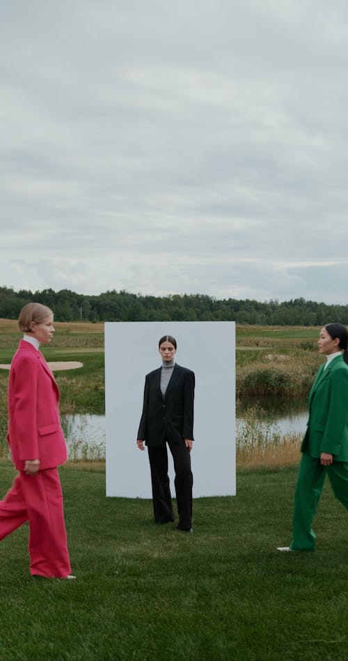 Women Standing by and walking near Wall on Grass