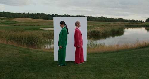 Women Standing by Wall on Grass and Raising Heads