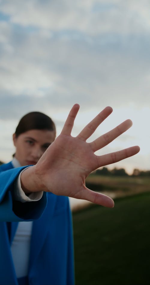 Woman Moving Hand in front of Camera and Standing on Grass with Women