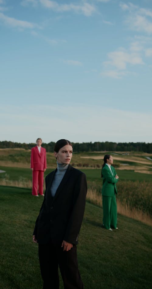 Women in Suits Standing on Grass under Clear Sky