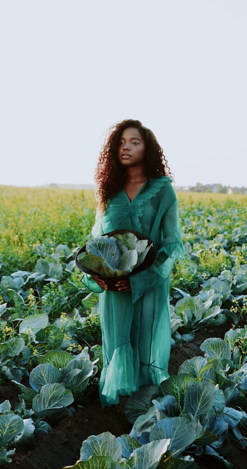A Woman in a Green Outfit Walking in a Cabbage Farm
