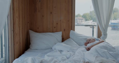 A Young Girl Getting Up from Bed while Looking at the Window