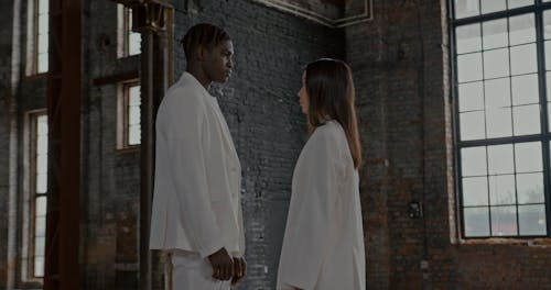 A Man and a Woman in White Suits Walking Away