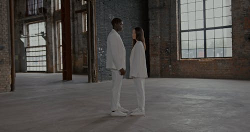 A Man and a Woman in White Suits Looking at Each Other