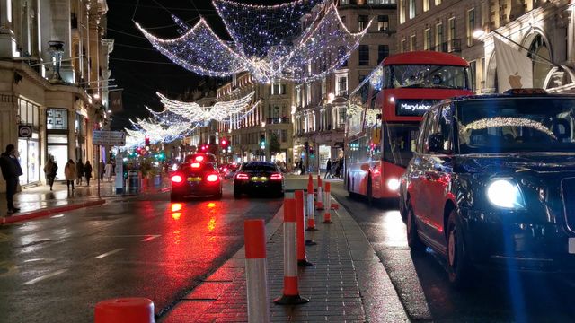 A London street at night with holiday lights and buses.