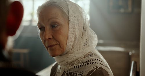 An Elderly Woman in a Headscarf Talking to a Person