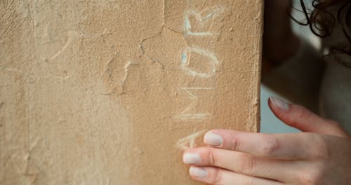 Close-up of a Beautiful Woman Touching a Word Carved on a Wall