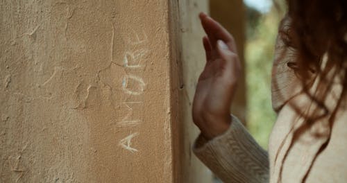 A Person Carving a Word on a Wall with a Stone