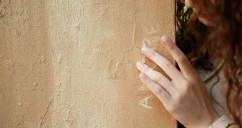 A Pretty Woman Touching a Word Carved on a Wall