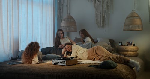A Group of Friends Lying on Bed Listening to Music