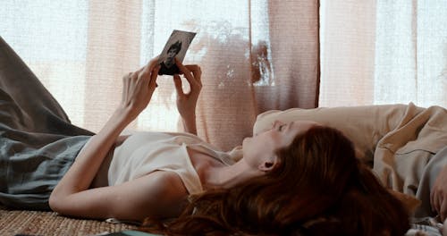Women Passing Around a Photo While Lying on a Bed
