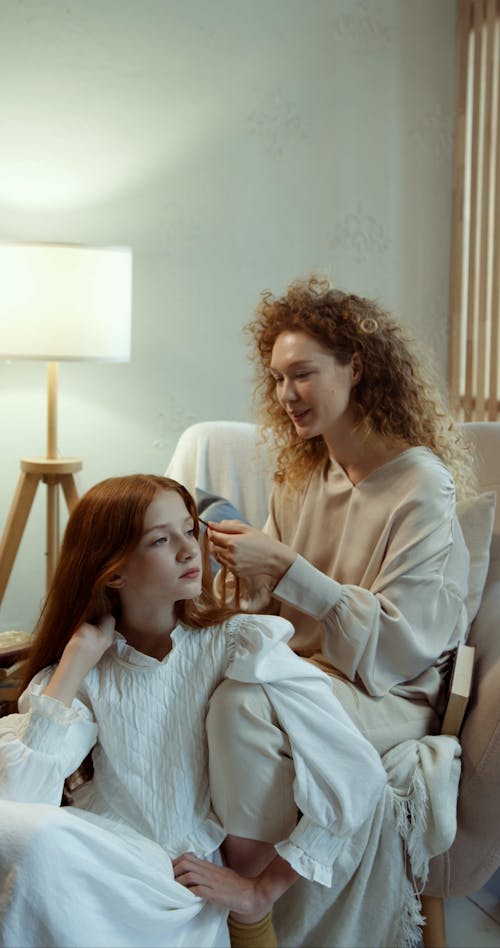 A Woman Braiding her Friend's Hair