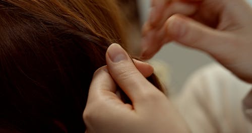 A Close-up Video of a Person Braiding a Girl's Hair