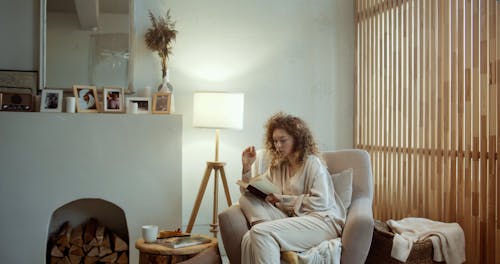 A Woman Reading a Book while Her Friend is Coming Over