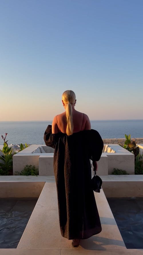 A Woman in a Black Dress Sitting in a Restaurant by the Sea