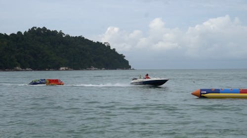 A Speed Boat Towing Inflatable Tube near the Shore