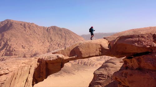 Tourist Walking on Natural Arch in Desert