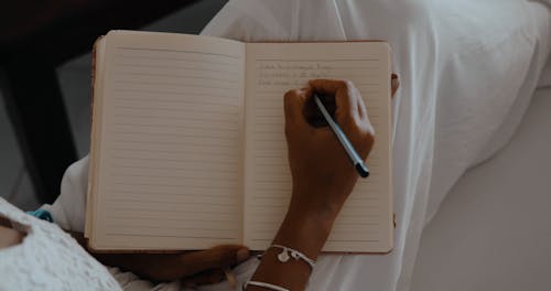 Close-up of Woman Writing in Notebook