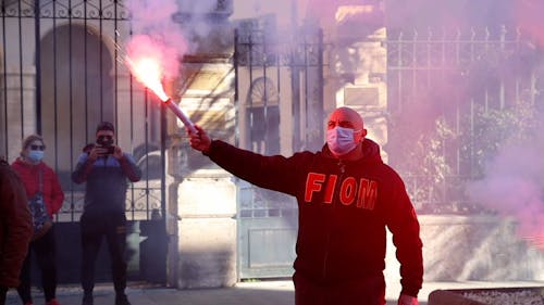 A Man Wearing a Face Mask Holding a Flare in the Street 