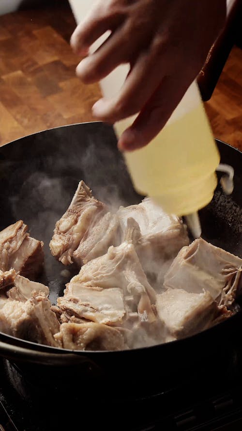 Person Cooking Meat in Frying Pan