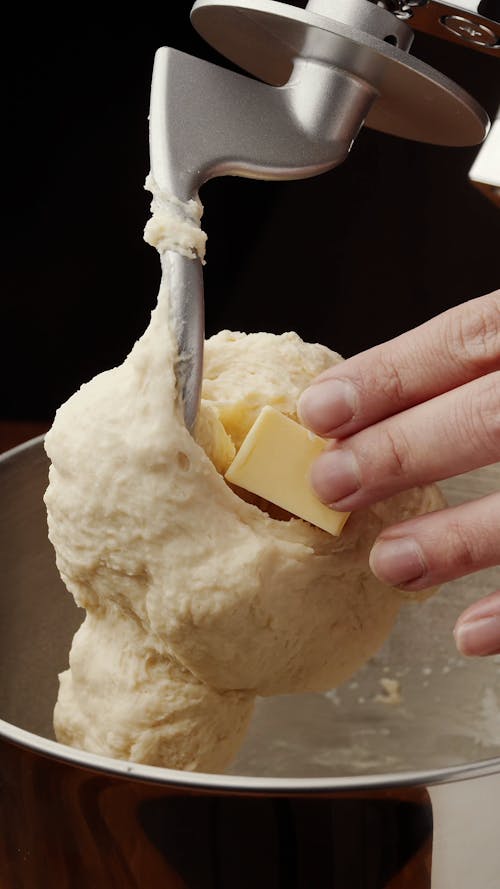 Person Adding Butter to Dough Maker