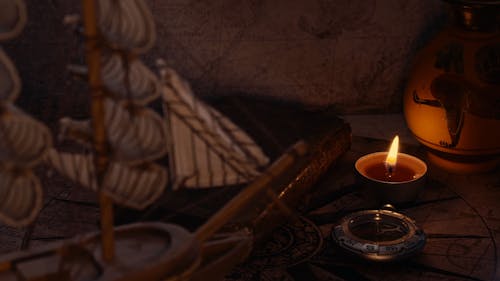 A Burning Candle by an Old Book and a Compass 