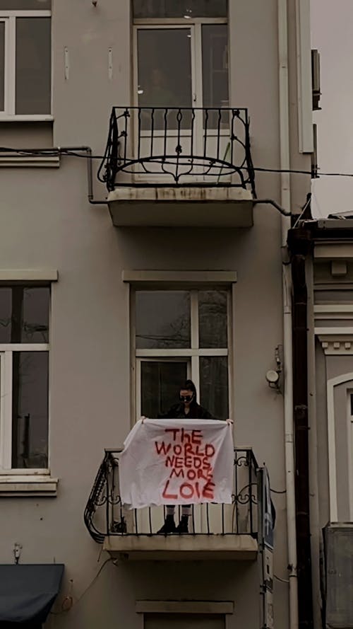 Woman on Balcony with Slogan The World Needs More Love