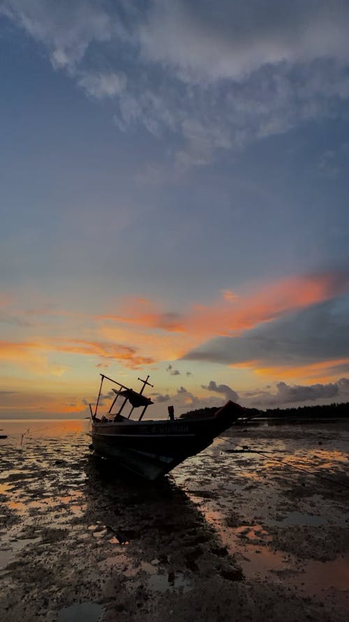 A Boat Stranded on the Beach under a Sunset Sky 