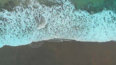 directly above view of sea waves stroking sandy beach
