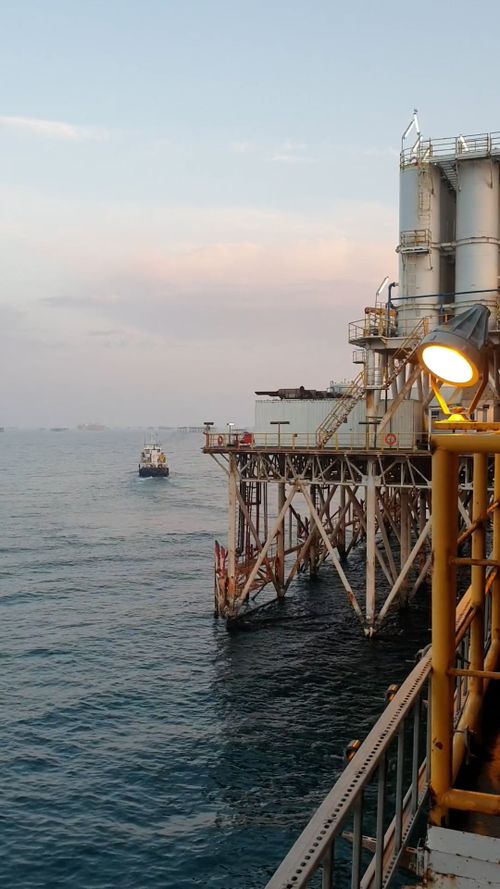 Workers in hard hats and high-visibility vests inspecting equipment at an oil refinery